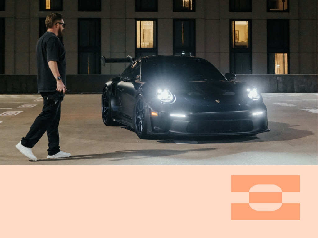 Automotive cinematographer Luke Asper walking toward a yellow Ferrari holding a camera, wearing AI-tailored IAMBIC MODEL T custom-fit shoes built for precision comfort during long shoot days.