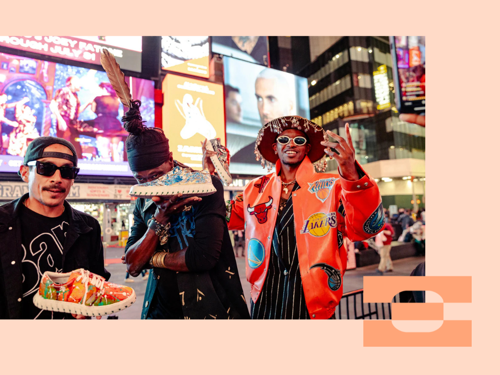 Art Gods collective members Phree Hester, Rio Sirah, and Manny Linx in Times Square showcasing their Supercar Art Gods x IAMBIC collaboration shoes, celebrating the fusion of art, technology, and cultural storytelling on a global stage.