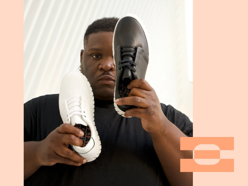 Stylist holding black and white IAMBIC MODEL T precision-fit shoes, showcasing AI-tailored craftsmanship and modern design contrast.