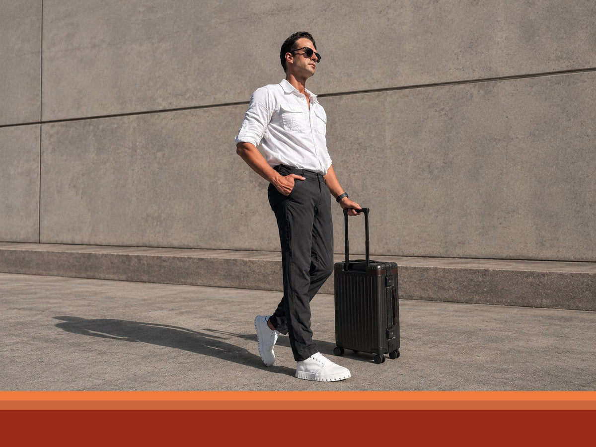 Traveler pulling a carry-on suitcase in white IAMBIC MODEL T business travel shoes
