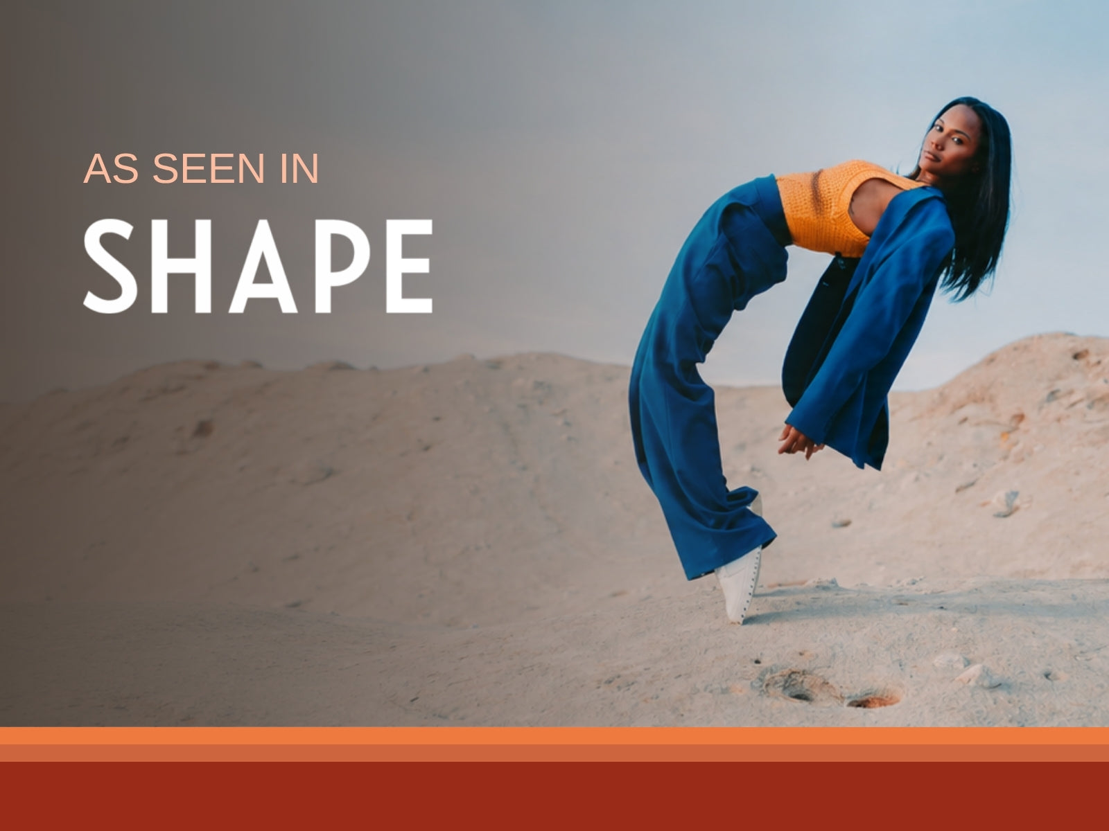 A dancer balanced on one toe in white IAMBIC precision-fit shoes on sand