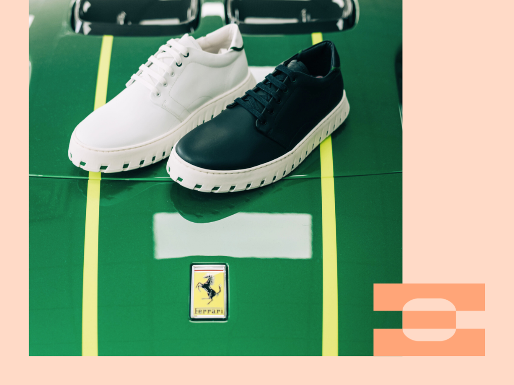 Black and white IAMBIC MODEL T precision-fit shoes photographed on a green supercar hood, highlighting motorsport-inspired design.