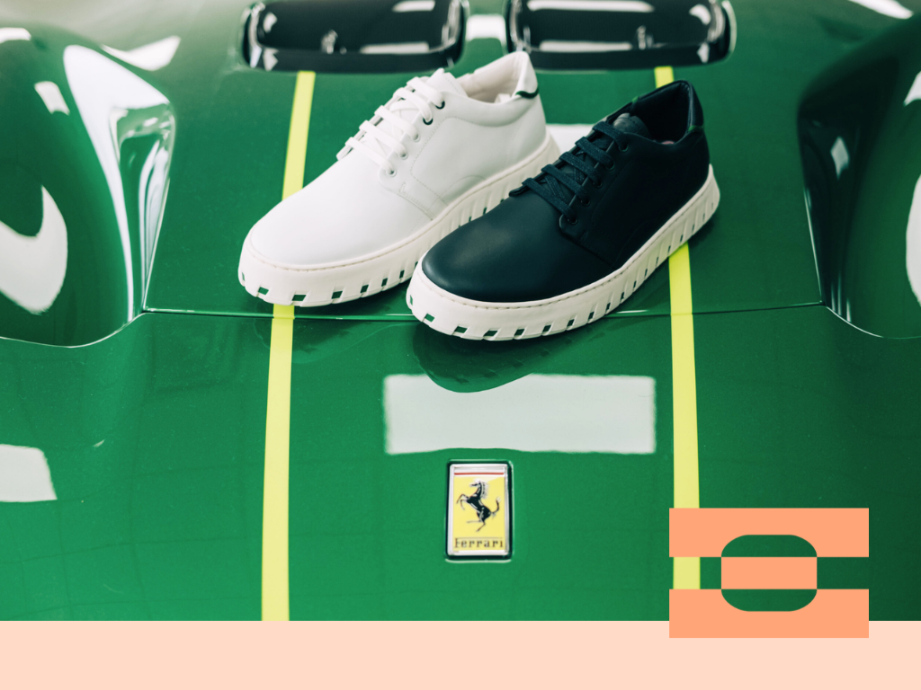 Black and white IAMBIC MODEL T precision-fit shoes photographed on a green supercar hood, highlighting motorsport-inspired design.