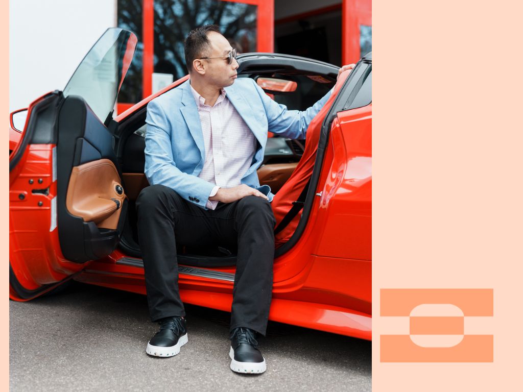 Motorsport Lab founder Ray Chang stepping out of a red supercar wearing IAMBIC MODEL T precision-fit shoes, symbolizing performance, luxury, and comfort engineered for travel.