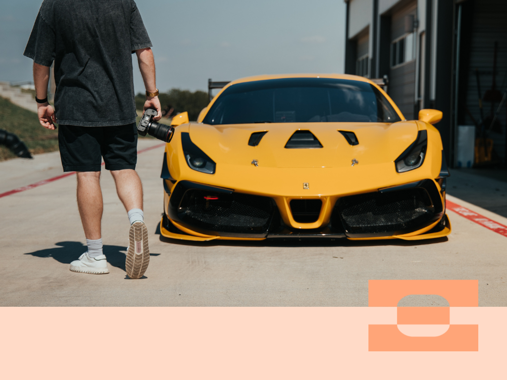 Automotive cinematographer Luke Asper walking toward a yellow Ferrari holding a camera, wearing AI-tailored IAMBIC MODEL T custom-fit shoes built for precision comfort during long shoot days.