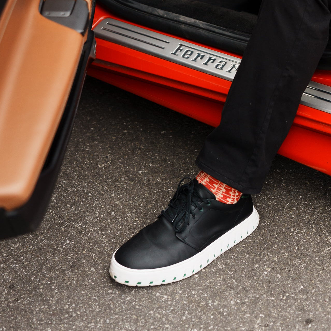 Person sitting inside a red Ferrari with IAMBIC MODEL T black shoes.
