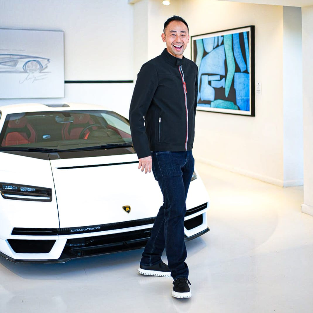 Ray standing next to a white Lamborghini in IAMBIC shoes